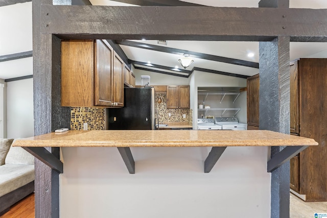 kitchen with vaulted ceiling with beams, tasteful backsplash, light countertops, independent washer and dryer, and a peninsula