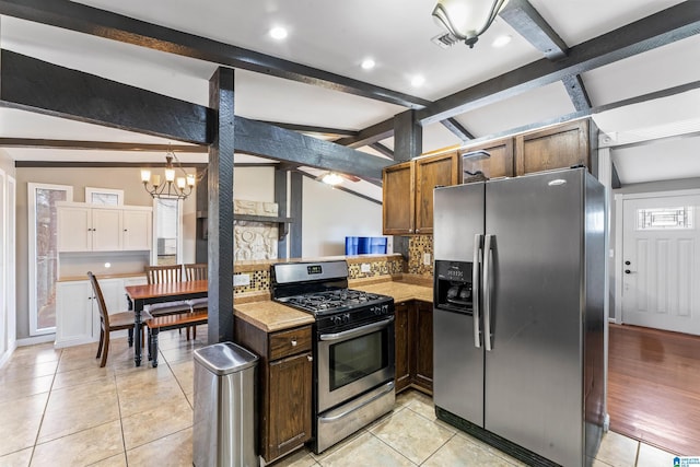 kitchen with light tile patterned floors, stainless steel appliances, light countertops, and decorative backsplash