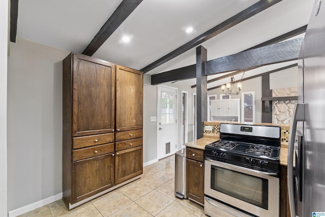 kitchen featuring lofted ceiling with beams, baseboards, appliances with stainless steel finishes, and light countertops