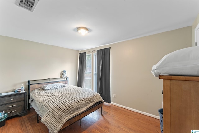 bedroom with wood finished floors, visible vents, and baseboards