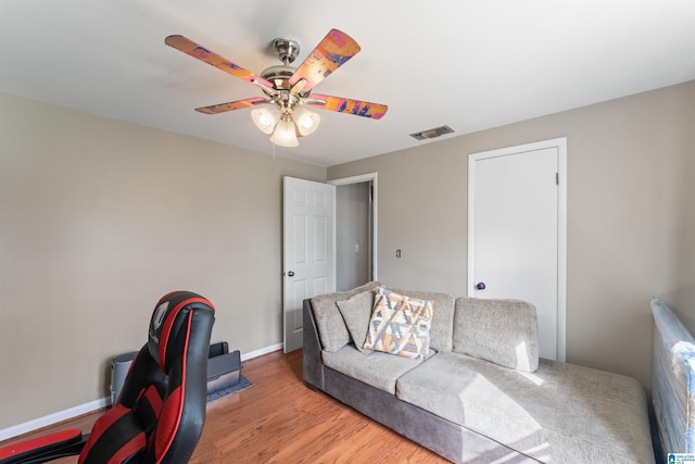 living area featuring light wood finished floors, baseboards, visible vents, and a ceiling fan