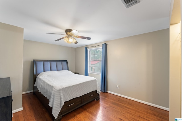 bedroom with a ceiling fan, wood finished floors, visible vents, and baseboards