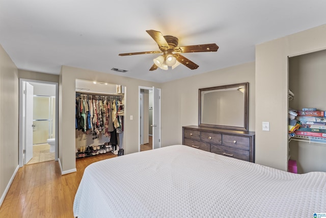 bedroom featuring a walk in closet, a closet, visible vents, light wood-type flooring, and baseboards