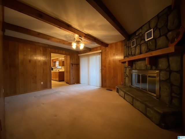 unfurnished living room featuring visible vents, a fireplace, wood walls, and beamed ceiling