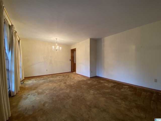 carpeted empty room featuring baseboards and a notable chandelier