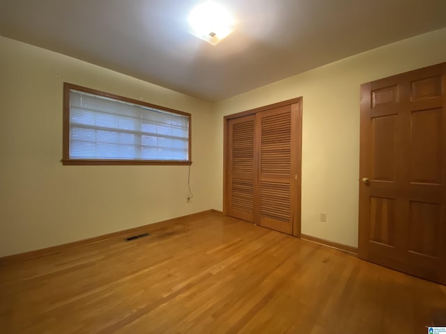 unfurnished bedroom featuring a closet, light wood-type flooring, visible vents, and baseboards