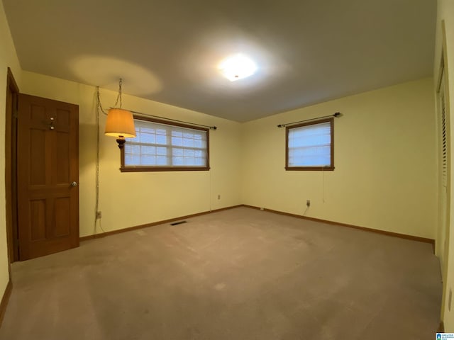 unfurnished bedroom featuring carpet floors, multiple windows, visible vents, and baseboards