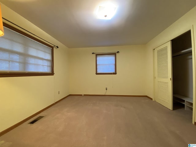 unfurnished bedroom with light colored carpet, a closet, visible vents, and baseboards