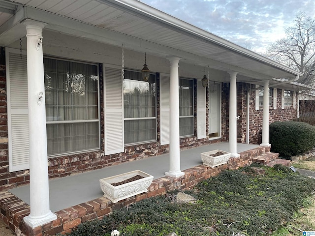 view of exterior entry with brick siding and a porch