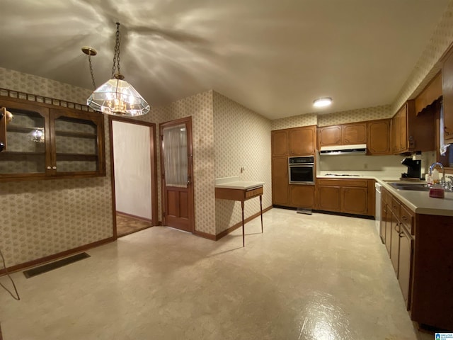 kitchen with oven, under cabinet range hood, a sink, visible vents, and wallpapered walls