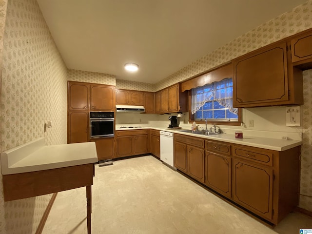 kitchen featuring wall oven, white dishwasher, a sink, and wallpapered walls