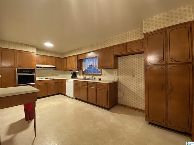 kitchen featuring under cabinet range hood, white appliances, light countertops, light floors, and wallpapered walls