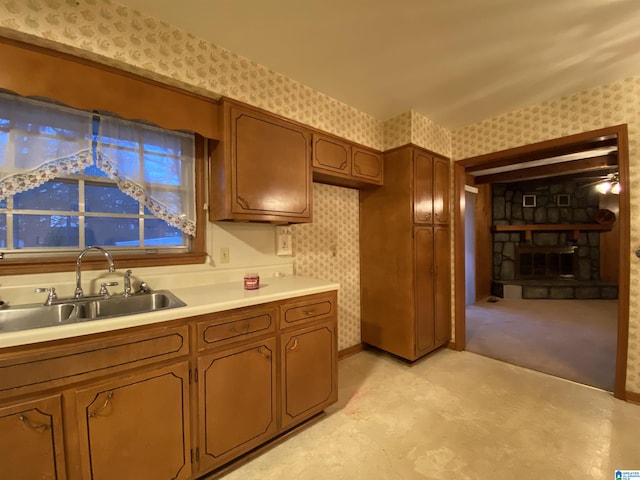 kitchen featuring light countertops, a fireplace, a sink, and wallpapered walls