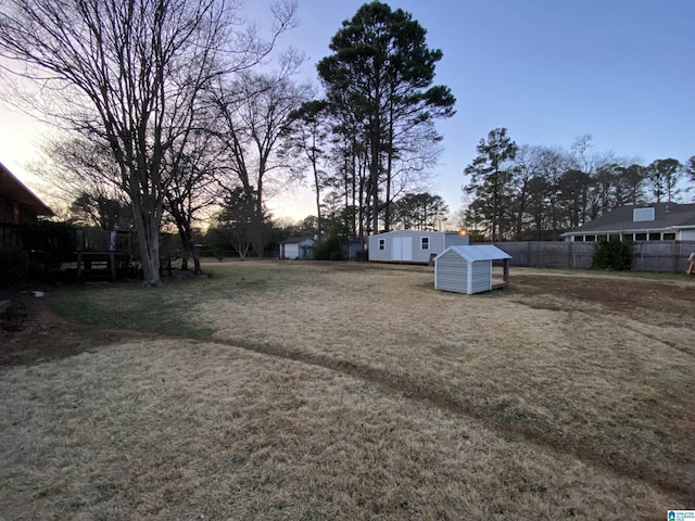 view of yard featuring a storage shed, an outdoor structure, and fence