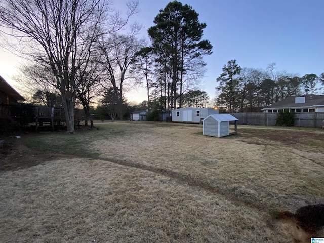 view of yard featuring an outbuilding, fence, and a storage shed