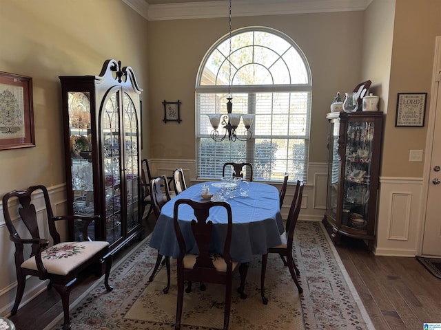 dining area with wainscoting, wood finished floors, an inviting chandelier, crown molding, and a decorative wall