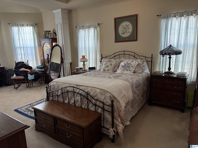 bedroom with decorative columns and light colored carpet