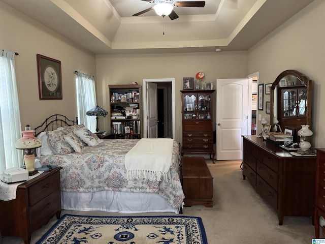 bedroom with ceiling fan, a raised ceiling, and light colored carpet