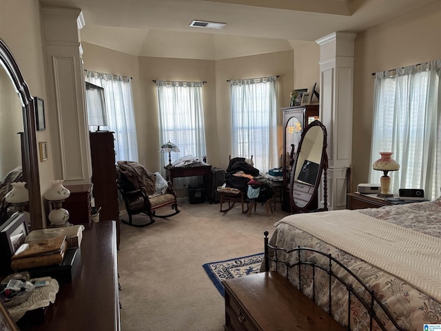 bedroom with light carpet, decorative columns, visible vents, and vaulted ceiling