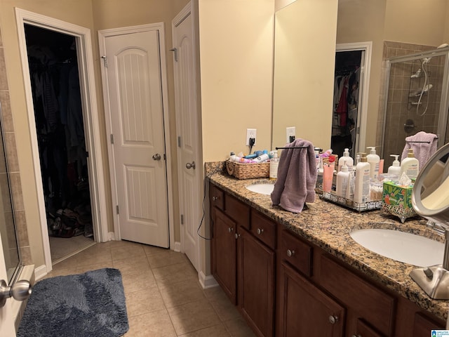 bathroom featuring double vanity, a spacious closet, a sink, a shower stall, and tile patterned flooring