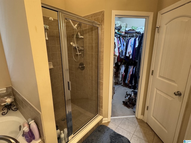 bathroom with a shower stall, a spacious closet, and tile patterned floors