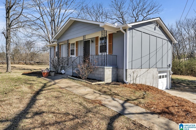 view of front of home with a front lawn, concrete driveway, covered porch, and an attached garage