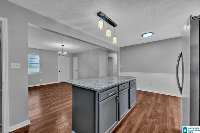 kitchen featuring dark wood-style floors, pendant lighting, gray cabinetry, freestanding refrigerator, and a kitchen island