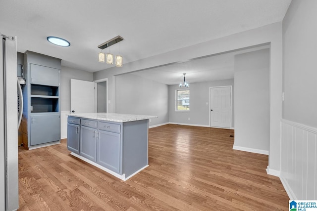 kitchen with light wood-style flooring, a kitchen island, gray cabinetry, and decorative light fixtures