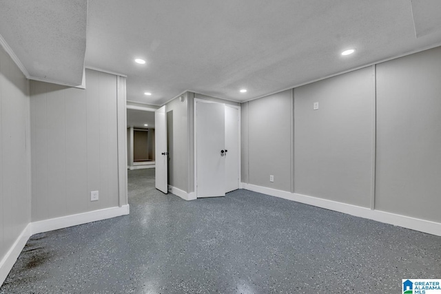 basement featuring baseboards, a decorative wall, a textured ceiling, and recessed lighting