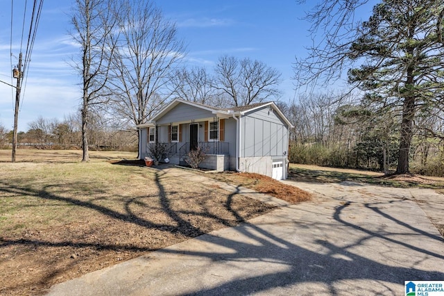 view of front of home with covered porch, concrete driveway, a front lawn, and a garage