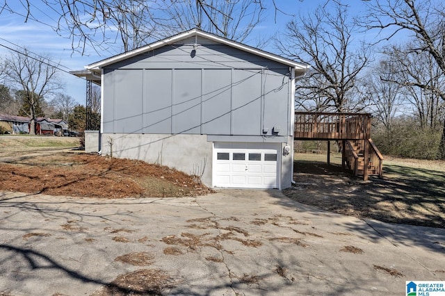 exterior space with a garage, concrete driveway, a deck, and stairs