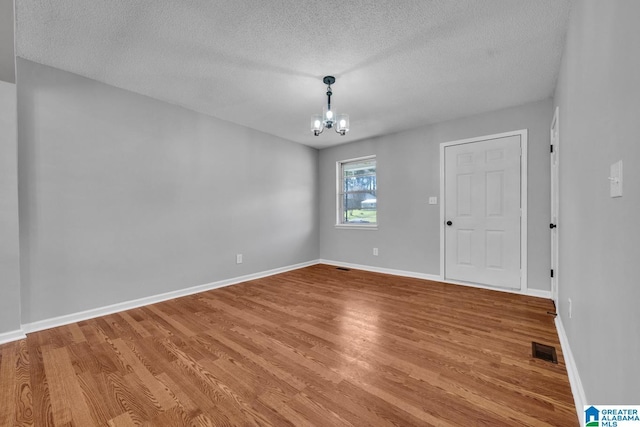 unfurnished room with baseboards, light wood finished floors, visible vents, and an inviting chandelier