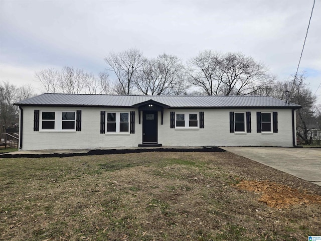 view of front facade with entry steps, metal roof, brick siding, and a front yard