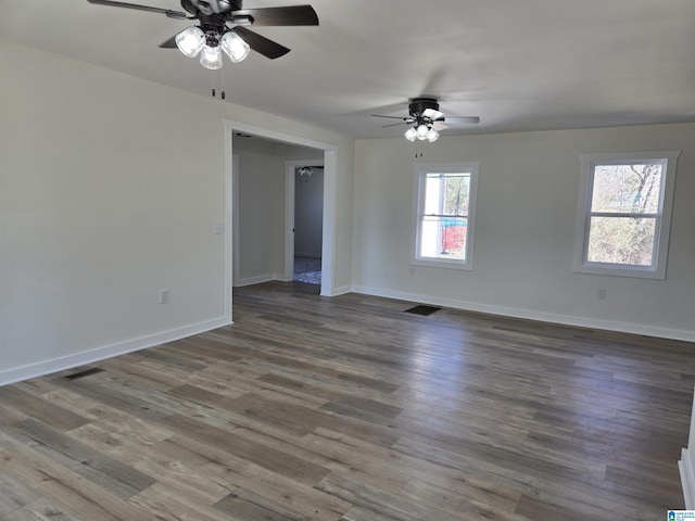 unfurnished room with dark wood finished floors, visible vents, and baseboards