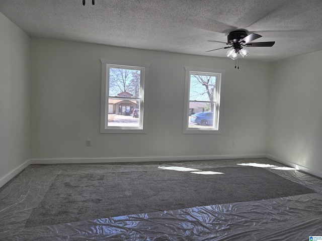 carpeted spare room with a textured ceiling, a ceiling fan, and baseboards