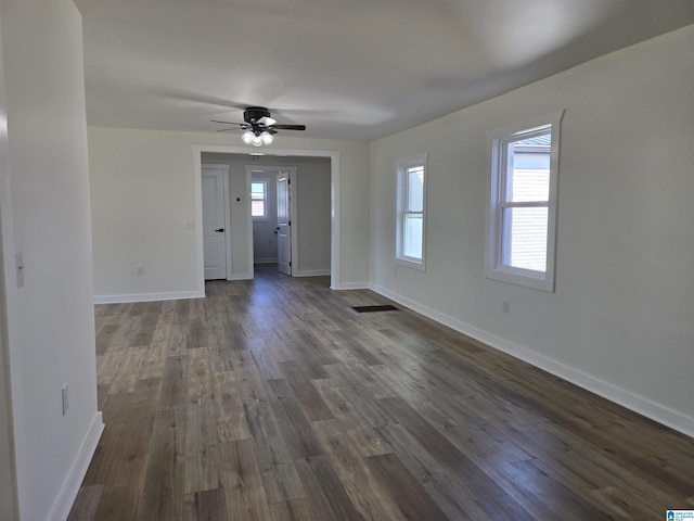 unfurnished living room featuring dark wood-style floors, a ceiling fan, visible vents, and baseboards