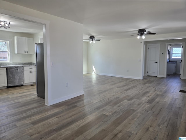 unfurnished living room with ceiling fan, baseboards, and wood finished floors