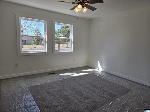 unfurnished room featuring ceiling fan, visible vents, and baseboards