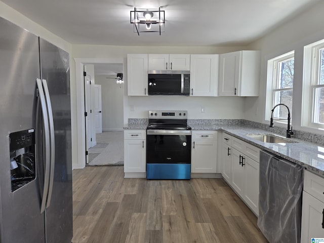 kitchen with stainless steel appliances, light wood-style floors, white cabinetry, and a sink