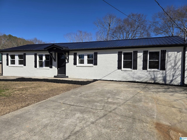 view of front of property with entry steps, metal roof, and brick siding