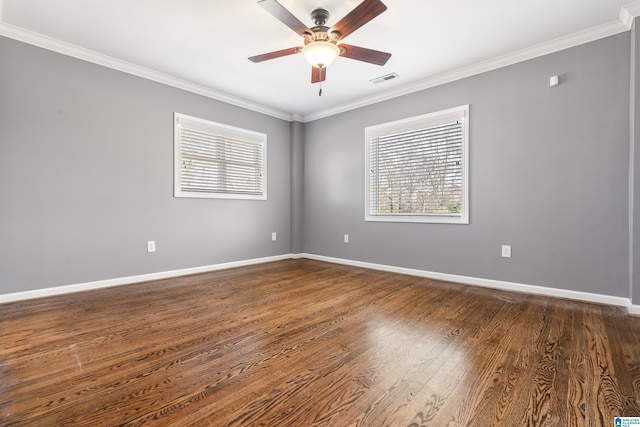 spare room featuring ceiling fan, visible vents, baseboards, ornamental molding, and dark wood finished floors