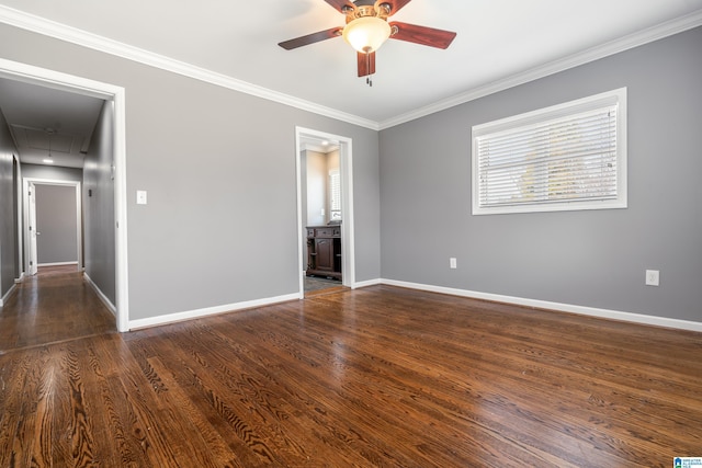 unfurnished room featuring dark wood-type flooring, a ceiling fan, baseboards, attic access, and crown molding