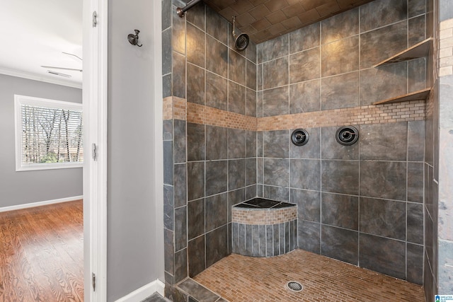 full bath featuring baseboards, a tile shower, and wood finished floors