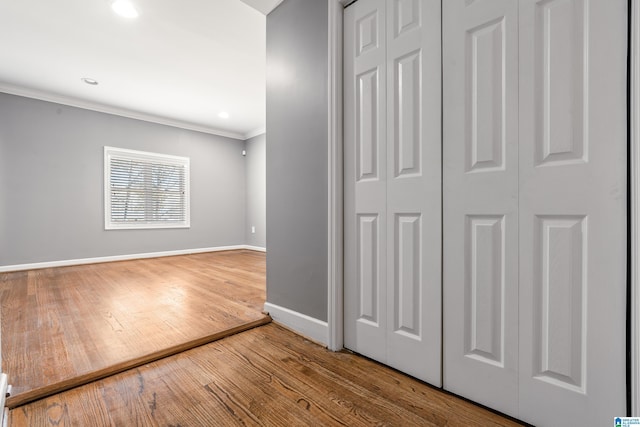 interior space featuring ornamental molding, a closet, baseboards, and wood finished floors