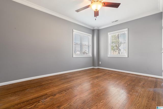 spare room with crown molding, visible vents, a ceiling fan, wood finished floors, and baseboards