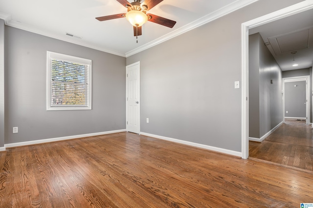 unfurnished room with baseboards, attic access, visible vents, and wood finished floors