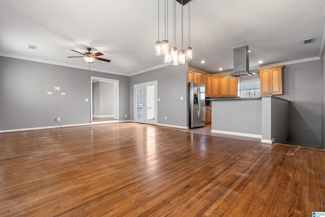 unfurnished living room with visible vents, crown molding, baseboards, and wood finished floors