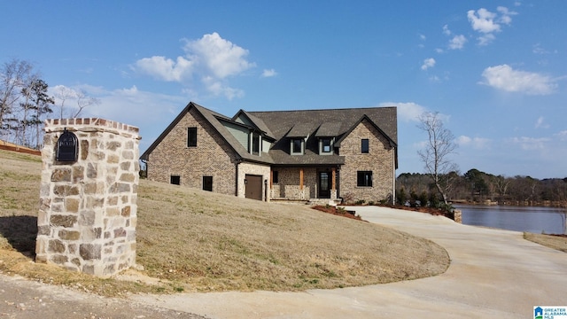 view of front facade featuring a front yard, concrete driveway, and a water view