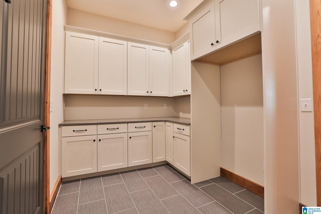 interior space featuring dark countertops, white cabinetry, baseboards, and recessed lighting