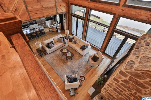 living area featuring wooden walls, high vaulted ceiling, and wood finished floors